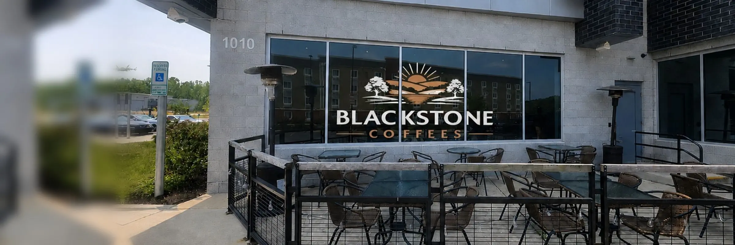 Blackstone Coffees storefront at 1010 Corporate Drive in Stafford, with the Blackstone Coffees logo on the front window above the fenced outdoor patio with tables and chairs
